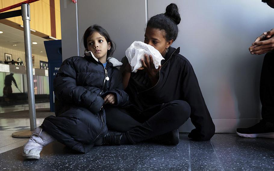 Venezuelan migrants Karen Malave and daughter Arril Brandelli, 7, eat food left by a volunteer on their seventh day of waiting inside Chicago’s 16th District police station, April 26, 2023.