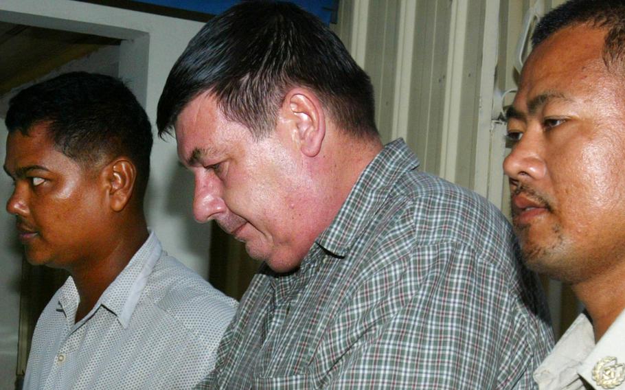 Marine Corps veteran Michael Joseph Pepe, center, is escorted by police in Phnom Penh, Cambodia, on June 19, 2006. Pepe, who has been in U.S. federal custody since 2007, was given a 210-year prison sentence on Monday, Feb. 14, 2022.