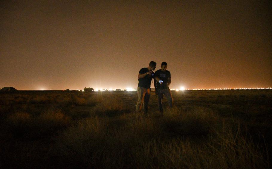 Army Spc. Joseph Neitz points out possible hiding spots for scorpions with Staff Sgt. Eric Bejarano while walking through the desert near Ali Al Salem Air Base in Kuwait on Nov. 28, 2022. 