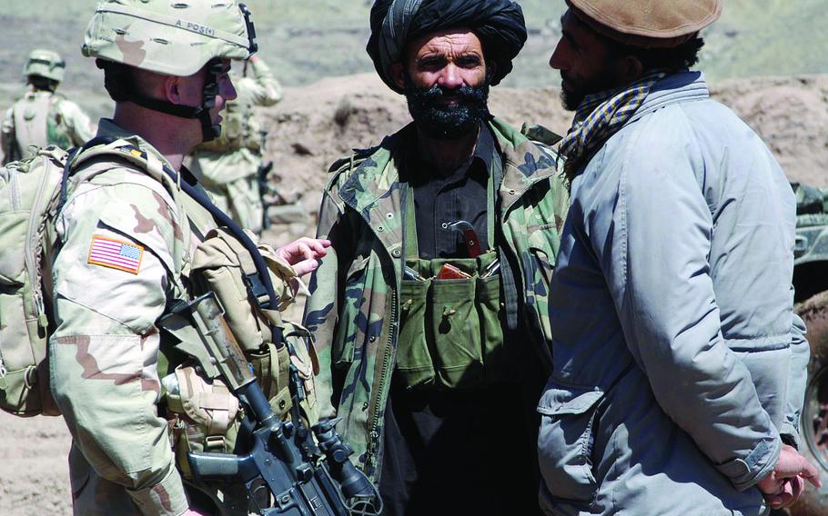 Capt. Jack Kilbride, left, of the 1st Battalion, 508th Infantry Regiment, uses a translator to talk to Naka police chief Jon Baz, center.