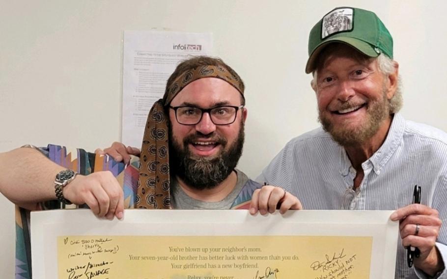 Writer-director Savage Steve Holland and superfan Brian Keil next to a signed “Better Off Dead” poster. 