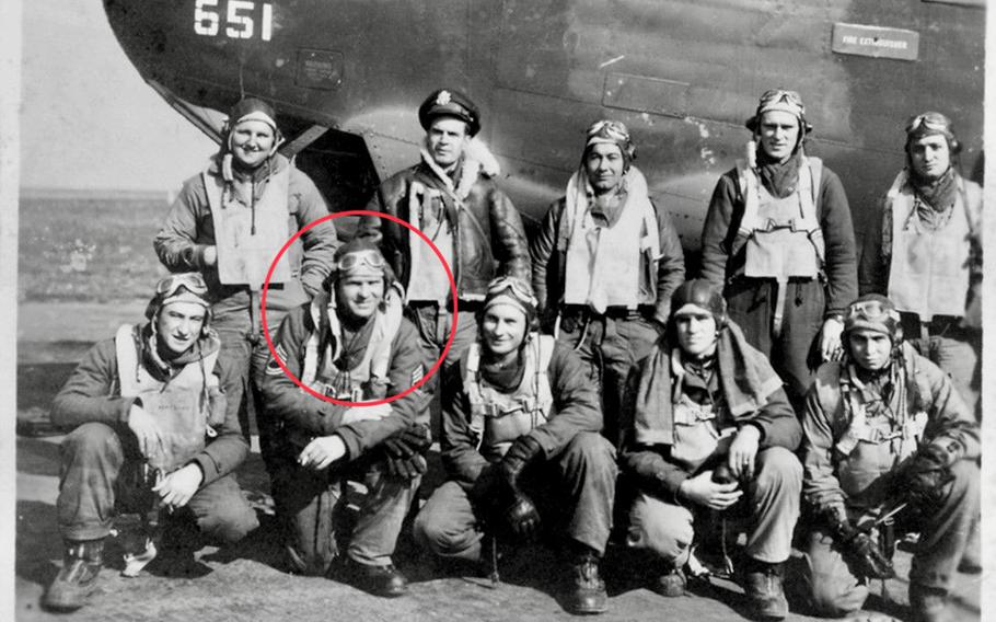 A black and white photo of a crew of personnel standing before an airplane.