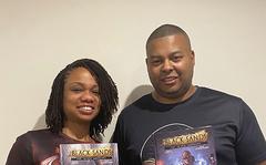 This photo provided by Black Sands Entertainment shows Manuel and Geiszel Godoy, founders of Black Sands Entertainment, with their flagship Black Sands comic book.  