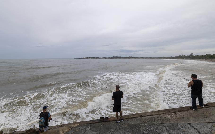 People fish along a beach shore.