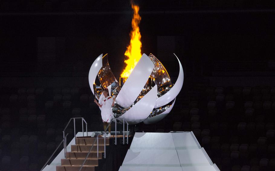 Tennis star Naomi Osaka of Japan stands in front of the Olympic flame after igniting it during the Tokyo 2020 opening ceremony. 