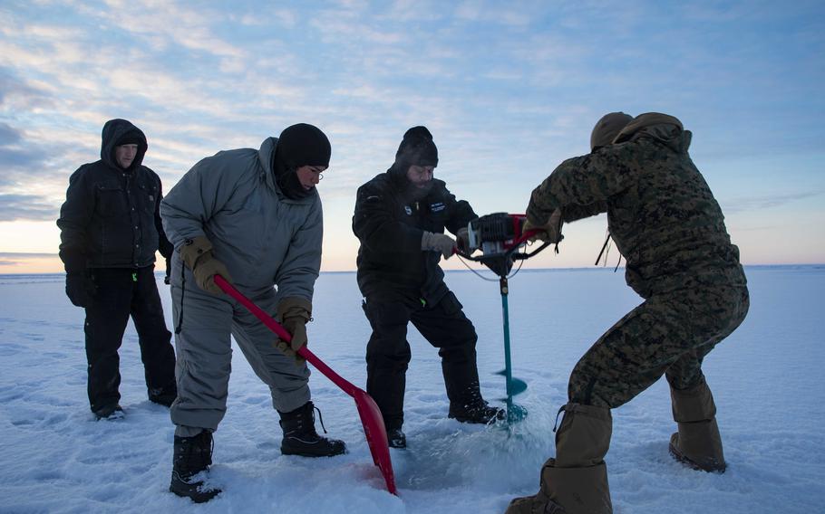 Sailors, Marines and members of the Arctic Submarine Laboratory dig a hole in the sea ice to prepare for the emergence of a submarine in the Beaufort Sea on March 4, 2022.