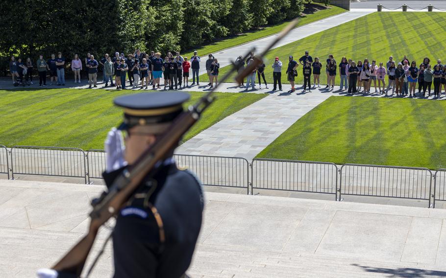 A soldier marches, with his rifle, in front of a crowd.