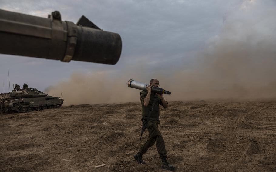 An Israeli soldier carries a tank shell near the border of Gaza on Oct. 14, 2023.