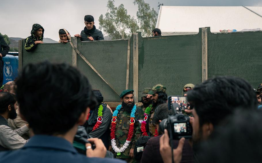 Taliban military official Mohammad Adnan Junudi, center with green beret, takes part in a Nov. 9, 2023, ceremony in front of a military truck carrying returnees' belongings. 