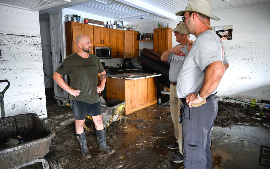 Three men talking as they stand in a flood-damaged apartment.