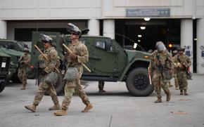 Troops outfitted with helmets, masks and other riot gear.
