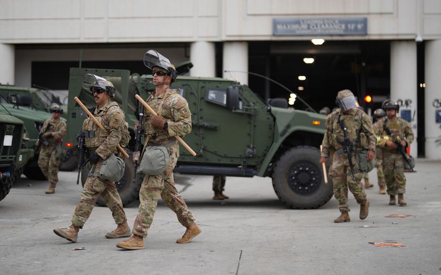 Troops outfitted with helmets, masks and other riot gear.