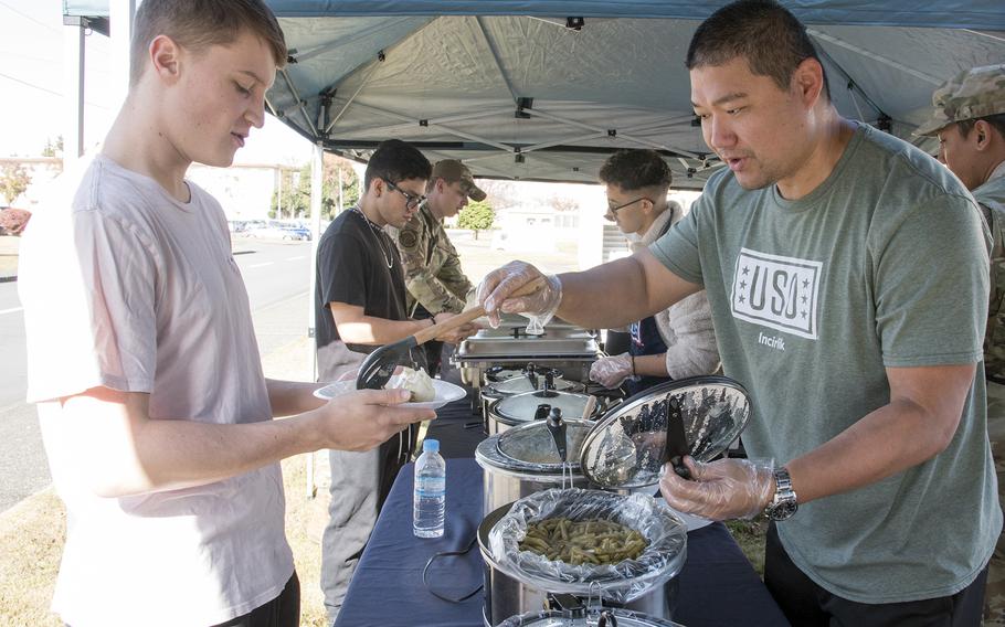 Air Force Staff Sgt. Jeffrey Hensye, a USO volunteer, serves a Thanksgiving meal to Airman 1st Class Avery Ryan at Yokota Air Base, Japan, Tuesday, Nov. 22, 2022.