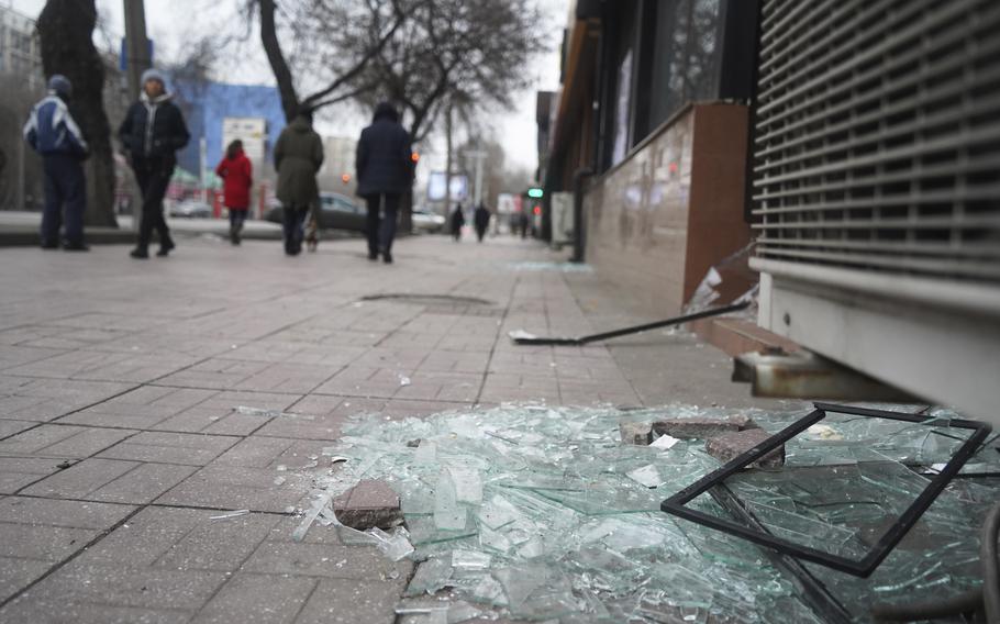 People walk past a shop with windows broken during clashes in Almaty, Kazakhstan, Monday, Jan. 10, 2022. Kazakhstan’s health ministry says over 150 people have been killed in protests that have rocked the country over the past week.