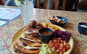 The birria tacos at Potro Lounge in Newmarket, England. The dish consists of four beef tacos served with guacamole, pico de gallo, two fried vegetables, chips, cabbage and a cup of birria sauce. 