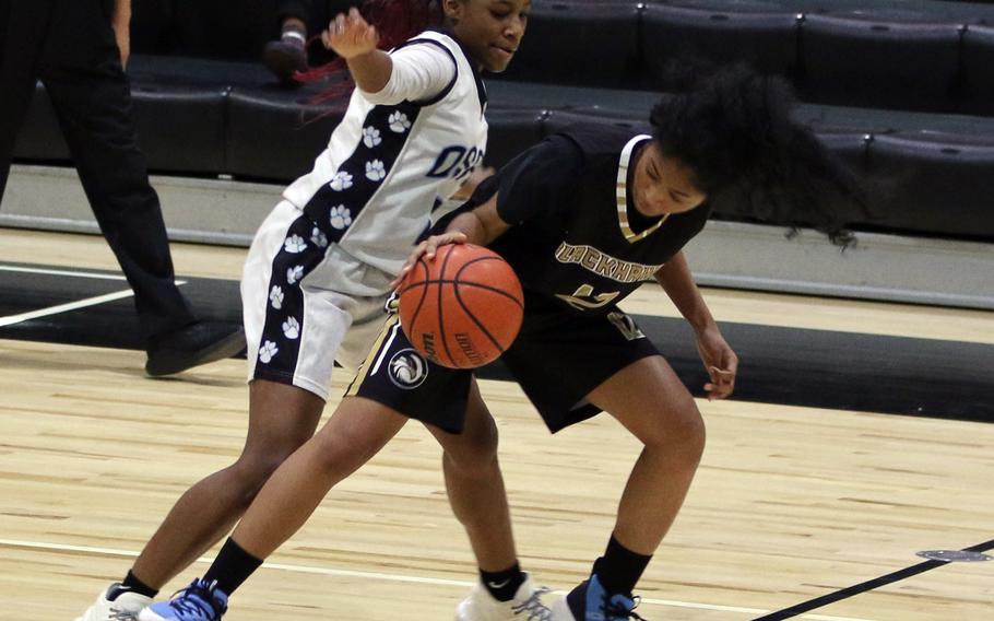 Humphreys Black’s Alexis Smalls fights to control the ball against Osan’s Tatiana Lunn during Saturday’s DODEA-Korea girls basketball game, won by the Cougars 34-30.