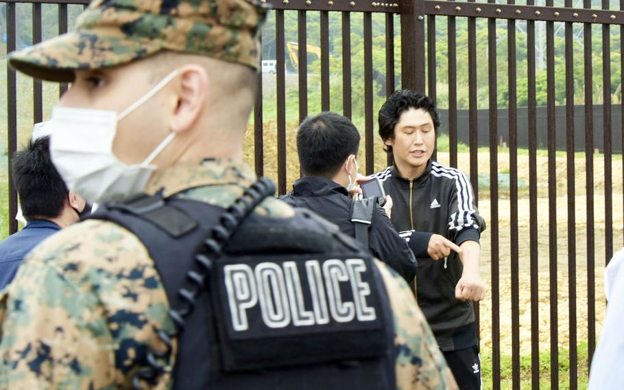 An unidentified man, barefoot and muddy in a black and white track suit, attempted to climb a steel fence within the grounds of Camp Foster, Okinawa, Wednesday, March 2, 2022. 