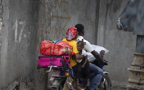 Residents travel on a motorbike as they flee their home to avoid clashes between armed gangs, in the Croix-des-Mission neighborhood of Port-au-Prince, Haiti, Thursday, April 28, 2022. Experts say the scale and duration of gang clashes, the power they are wielding and the amount of territory they control has reached levels not seen before. (AP Photo/Odelyn Joseph)