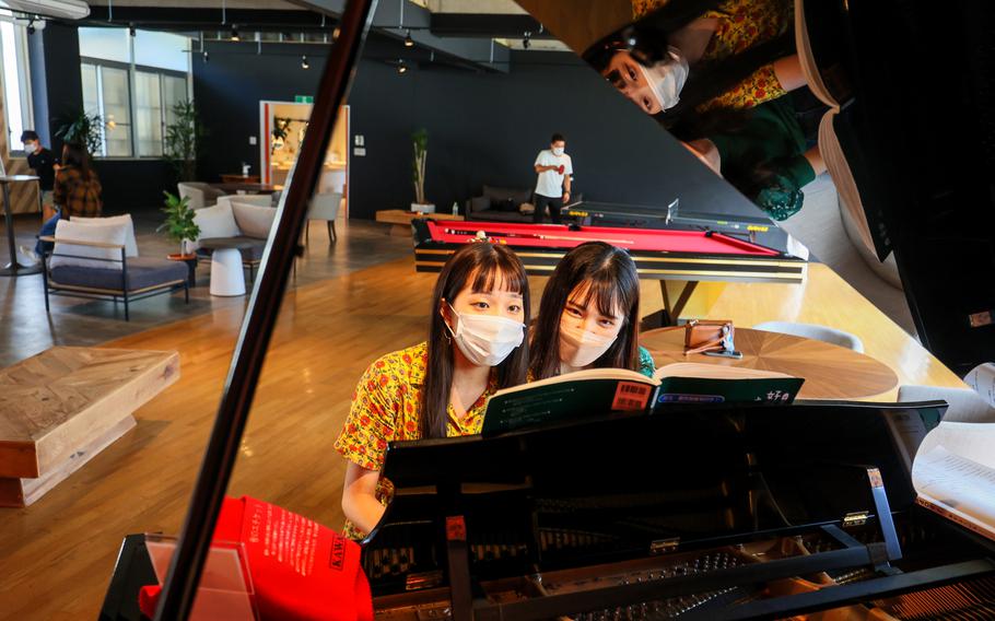 Visitors play a piano that used to belong to the school. 