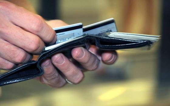 A hand pulls a credit card from a wallet.