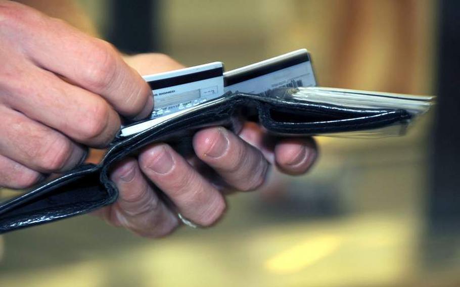 A hand pulls a credit card from a wallet.