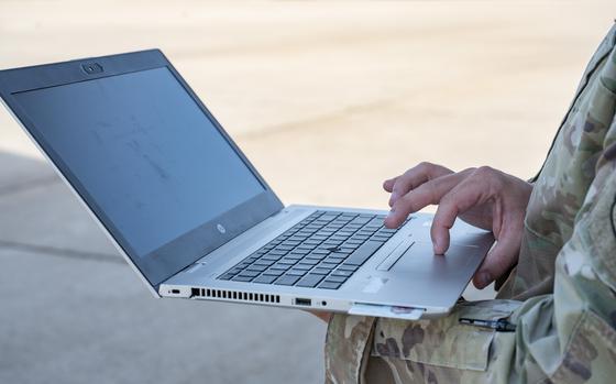 A close-up of a laptop being held in the air, supported by one hand while the other hand uses the trackpad.