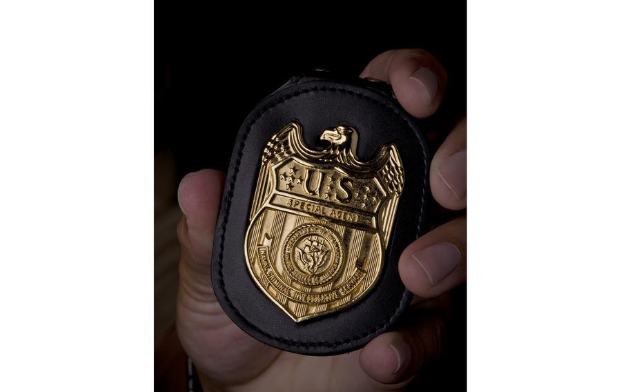 A close-up of a badge that reads “Special Agent” and “Naval Criminal Investigative Service.”