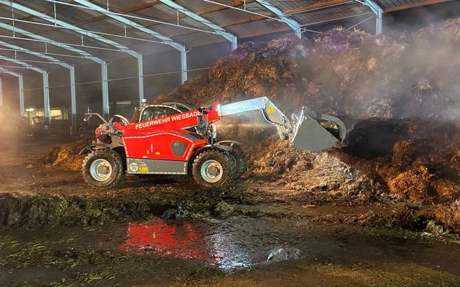 Crews use heavy equipment to extinguish hot spots at the scene of a fire at an agricultural storage area in Delkenheim, Germany, early Tuesday, Dec. 28, 2021. 