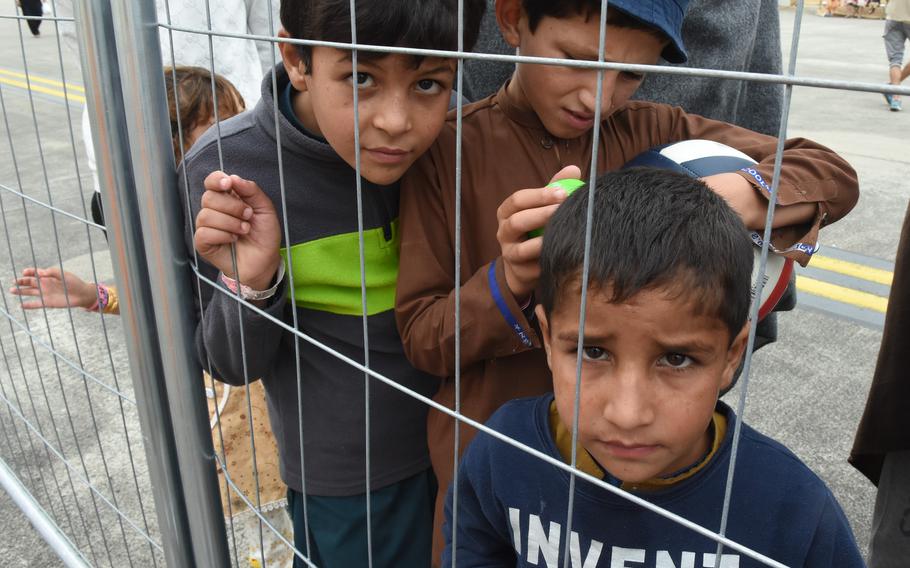 Children stare out from behind a fence inside a temporary living facility on the flight line at Ramstein Air Base, Germany, Aug. 23, 2021. About 7,000 evacuees had arrived by Monday, while some U.S. citizens and families left on flights to the United States.