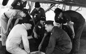 [PUBLISHED CAPTION: Crew members and volunteer "scanners' who flew a six-hour search mission Sunday for the missing Flying Tiger Super Constellation talk over their mission at Clark AB, P.I. They are (kneeling, from left) Capt. Theodore Stewart, 405th Fighter Wing pilot; A/1C James C. Johnson, crew chief; A/3C Lawrence L. Clatchey, and Capt. Lawrence R. Brosy, copilot. Others are (from left) A/2C Robert L. Jones, A/3C Dennis Jones, A/3C David K. Crausby and A/3C Edward M. Raquel, assistant crew chief. Pacific Stars and Stripes reporter S/Sgt. Robert G. Fisher of the Philippines Bureau accompanied the search mis-mission [sic]. 03/20/1962]; Crew members and volunteer "scanners" talk over the six-hour search and rescue mission searching for the Flying Tiger Airline Super Constellation that disappeared over the Western Pacific Ocean March 16, 1962. The missing plane - which was chartered by the U.S. Army - was transporting 96 military passengers and had 9 crew members on board. The crew pictured here after their return to Clark Air Base are (kneeling, from left) Capt. Theodore Stewart, 405th Fighter Wing pilot; Airman First Class James C. Johnson, crew chief; Airman Third Class Lawrence L. Clatchey, and Capt. Lawrence R. Brosy, copilot. Others are (from left) Airman Second Class Robert L. Jones, Airman Third Class Dennis Jones, Airman Third Class David K. Crausby and Airman Third Class Edward M. Raquel, assistant crew chief. Pacific Stars and Stripes reporter Staff Sgt. Robert G. Fisher (not pictured) of the Philippines Bureau accompanied the search mission. [cg]