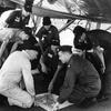 [PUBLISHED CAPTION: Crew members and volunteer "scanners' who flew a six-hour search mission Sunday for the missing Flying Tiger Super Constellation talk over their mission at Clark AB, P.I. They are (kneeling, from left) Capt. Theodore Stewart, 405th Fighter Wing pilot; A/1C James C. Johnson, crew chief; A/3C Lawrence L. Clatchey, and Capt. Lawrence R. Brosy, copilot. Others are (from left) A/2C Robert L. Jones, A/3C Dennis Jones, A/3C David K. Crausby and A/3C Edward M. Raquel, assistant crew chief. Pacific Stars and Stripes reporter S/Sgt. Robert G. Fisher of the Philippines Bureau accompanied the search mis-mission [sic]. 03/20/1962]; Crew members and volunteer "scanners" talk over the six-hour search and rescue mission searching for the Flying Tiger Airline Super Constellation that disappeared over the Western Pacific Ocean March 16, 1962. The missing plane - which was chartered by the U.S. Army - was transporting 96 military passengers and had 9 crew members on board. The crew pictured here after their return to Clark Air Base are (kneeling, from left) Capt. Theodore Stewart, 405th Fighter Wing pilot; Airman First Class James C. Johnson, crew chief; Airman Third Class Lawrence L. Clatchey, and Capt. Lawrence R. Brosy, copilot. Others are (from left) Airman Second Class Robert L. Jones, Airman Third Class Dennis Jones, Airman Third Class David K. Crausby and Airman Third Class Edward M. Raquel, assistant crew chief. Pacific Stars and Stripes reporter Staff Sgt. Robert G. Fisher (not pictured) of the Philippines Bureau accompanied the search mission. [cg]