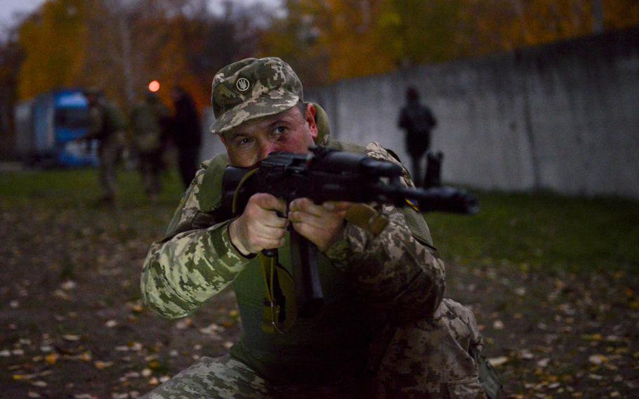 A Ukrainian soldier covers for his squad under simulated fire as they retrieve a casualty during training at a site on the outskirts of Kyiv, on Oct. 27, 2022.