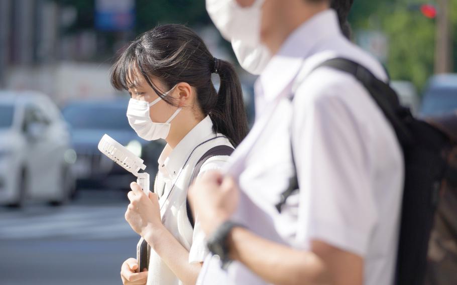 A woman employs a small electronic fan against the heat in central Tokyo on June 28, 2020.