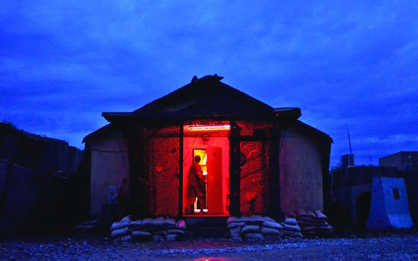 Combat Outpost Sabari, Afghanistan, Apr. 19, 2012: Spc. Jason White walks into a barracks building at Combat Outpost Sabari, Khost province. All exterior lights are painted red or turned off at night for minimum visibility.