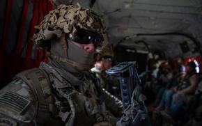 A uniformed soldier sits in a military vehicle.