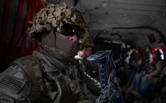 A uniformed soldier sits in a military vehicle.