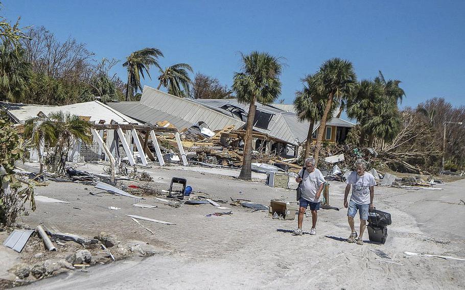 Residents walk along Estero Boulevard with suitcases as they leave the Fort Myers Beach Island on Friday September 30, 2022, two days after Hurricane Ian hit Florida’s west coast as a Category 4 storm.