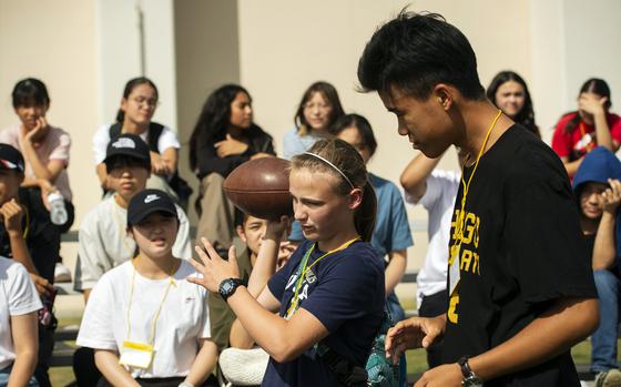 Elizabeth Shoop shows Kota Tsuruhara how to throw a spiral during the Student Educational Exchange and Dialogue camp at Matthew C. Perry High School, Marine Corps Air Station Iwakuni, Japan, Sept. 23, 2023.