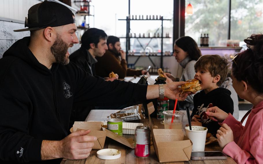 Tyler Connelly, 37, left, shares a bite of his fried chicken sammie with 2-year-old Kade Connelly. 