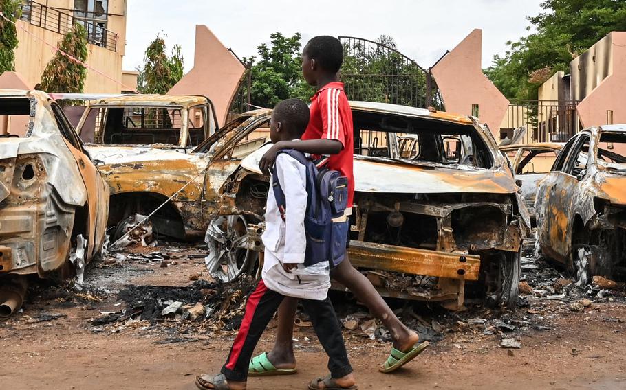Children walk past burned cars outside the headquarters of president Bazoum’s Nigerien Party for Democracy and Socialism in Niamey on Monday, Aug. 7, 2023. Niger’s military rulers Monday were in defiance of an ultimatum to restore the elected government as the threat of possible military intervention was still on the table.