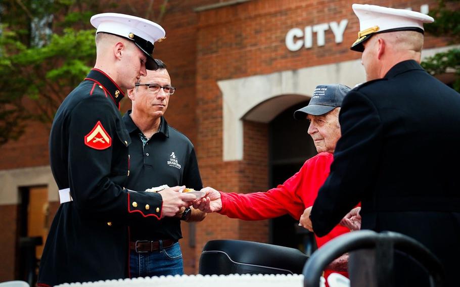 Marines help guide the hand of a veteran.