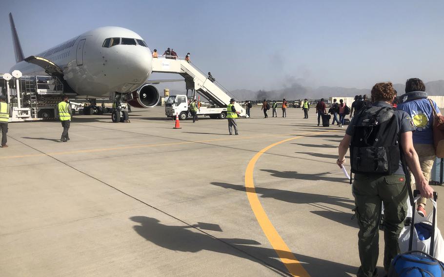 People board a plane chartered by the U.S. government at the airport in Kabul as they prepare to evacuate Afghanistan, Aug. 15, 2021.