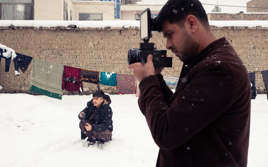 Two videographers working for “Kabul Lovers” take video as snow falls in Kabul, Afghanistan.