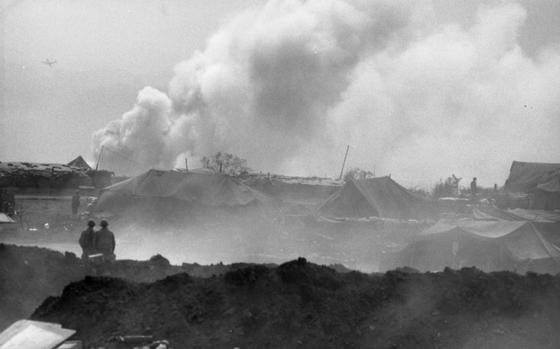 Khe Sanh, South Vietnam, Mar. 3, 1968: Two Marines watch as smoke from a burning supply pit that received a direct hit by North Vietnamese artillery rises into the sky. In the foreground tents and earth - protection walls, perimeter of Khe Sanh base. 

Looking for Stars and Stripes’ coverage of the Vietnam War? Subscribe to Stars and Stripes’ historic newspaper archive! We have digitized our 1948-1999 European and Pacific editions, as well as several of our WWII editions and made them available online through https://starsandstripes.newspaperarchive.com/

META TAGS: Vietnam War; battle; war; Khe Sanh; combat; Tet offensive; USMC; Marine base; Marines; supply base; mortar attack; rocket attack