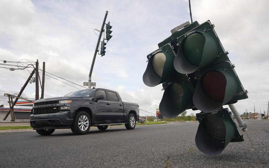 Traffic passes by a traffic light hanging from a cable after Hurricane Ida moved through Monday, Aug. 30, 2021, in LaPlace, La. 