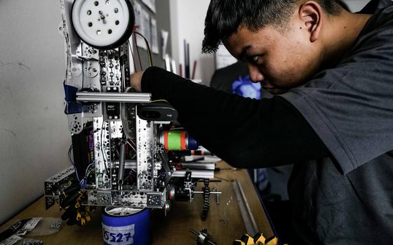 Deylan Acasio makes adjustments to the Ramstein robotics team's robot, March 18, 2024, at Ramstein Air Base, Germany. The robot's design won the team a spot at the First Tech Challenge World Championships in Houston, where it will compete against dozens of other designs.