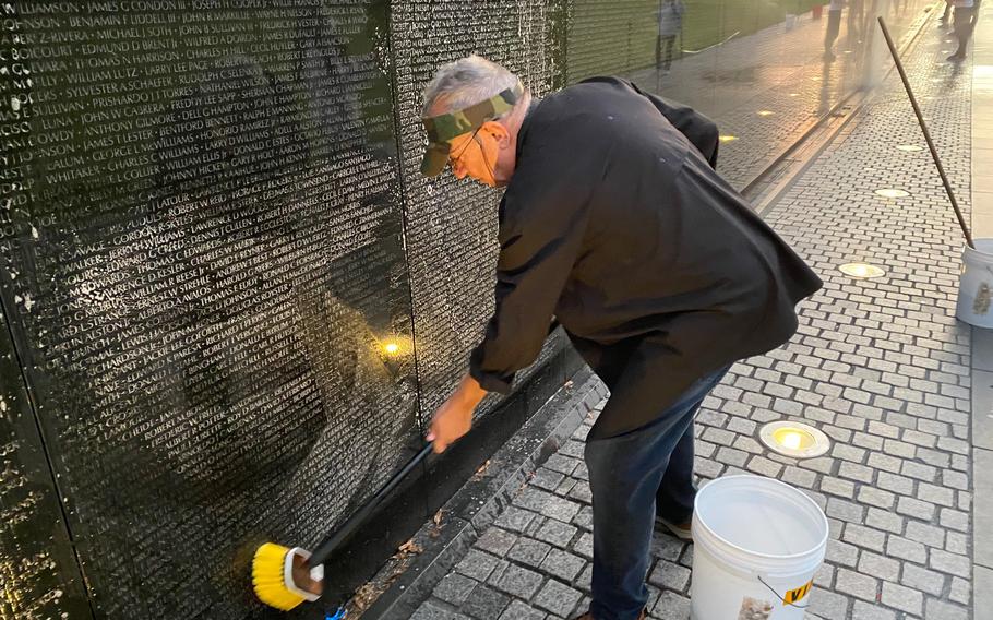 Jan Scruggs, founder of the Vietnam Veterans Memorial Fund, cleans the memorial’s wall.