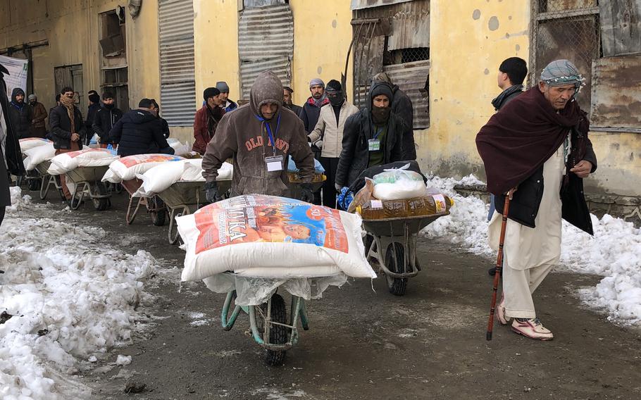 Mahmad Ali, a disabled war veteran, slowly accompanies the wheelbarrow of donated food he has just received in Kabul on Jan. 4, 2022. 
