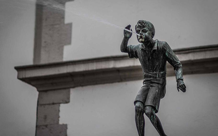 The Schaengelbrunnen is a beloved fountain on the square next to City Hall in Koblenz, Germany. It is topped by a little boy, known as Schaengel, who spits water at passers-by and has become emblematic of the city.