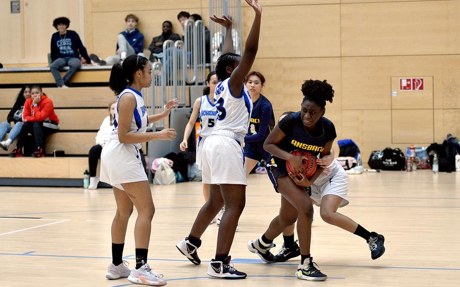 Ansbach sophomore Elizabeth Agudzi-Addo holds onto the ball under duress from pressure by Hohenfels defenders during pool-play action of the DODEA European basketball championships on Feb. 14, 2024, at the Wiesbaden Sports and Fitness Center on Clay Kaserne in Wiesbaden, Germany.